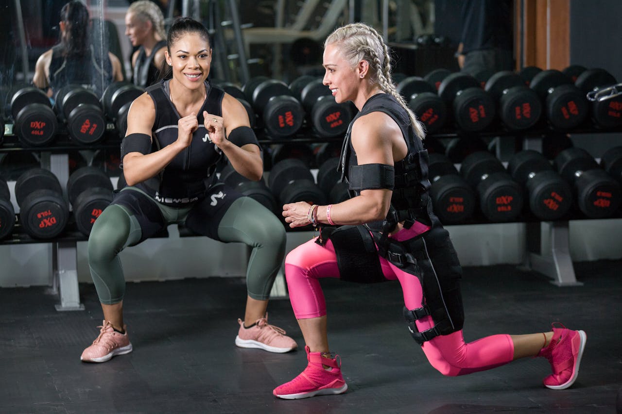 services-04 Two women engaged in strength training at a gym, showing determination.
